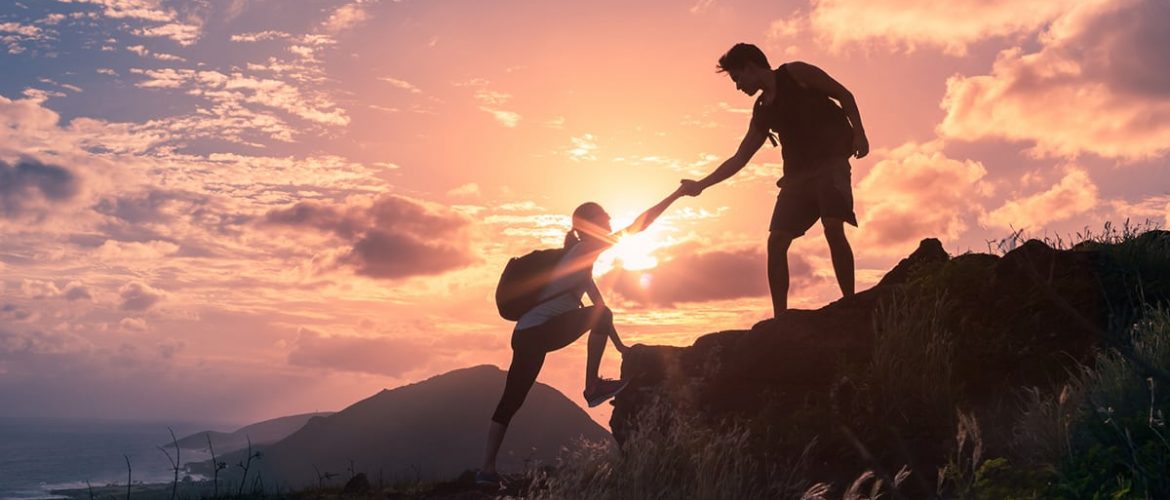 Man-giving-hand-to-woman-on-mountain-iStock-667315360